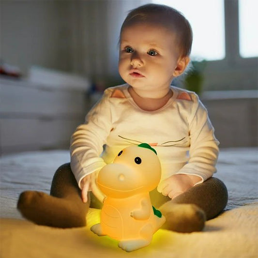 enfant assis avec sa veilleuse bebe dinosaure