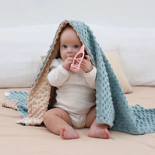 bebe assis jouet avec couverture bleue rose sur tete